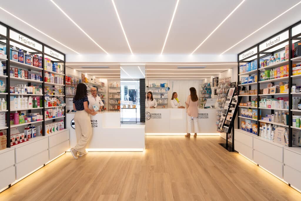 Farmacia con zona de atención al cliente, estanterías iluminadas y diseño moderno. Murcia